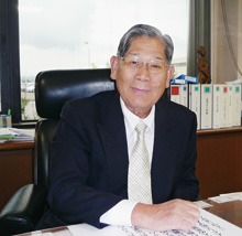 代表取締役社長の安達進氏。後ろの棚にはゴルフや 各種交流会などの資料が並ぶ